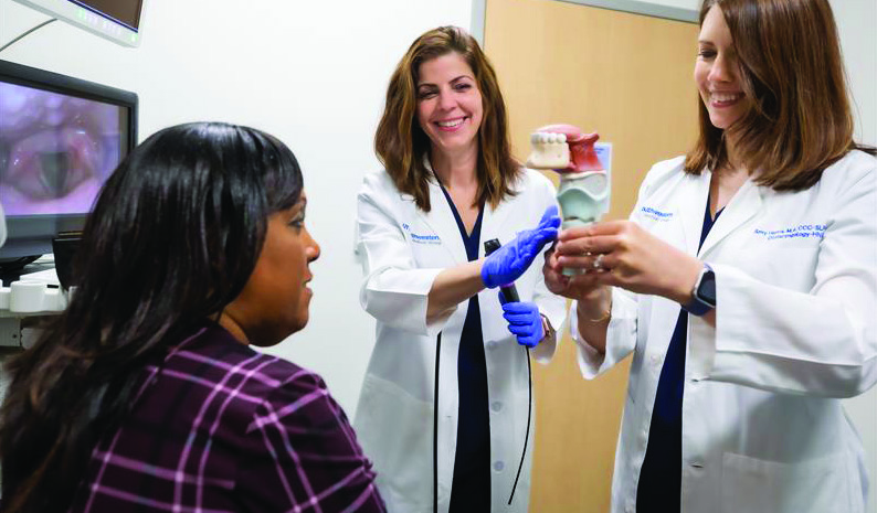 Two doctors demonstrate a model of the human mouth and throat to a patient