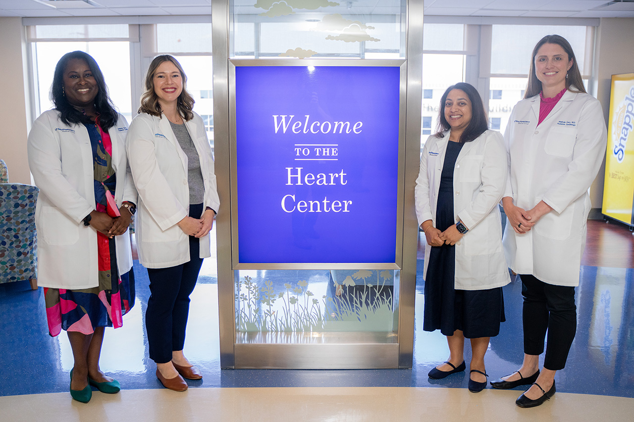 Cardiology faculty posed around the purple heart center sign