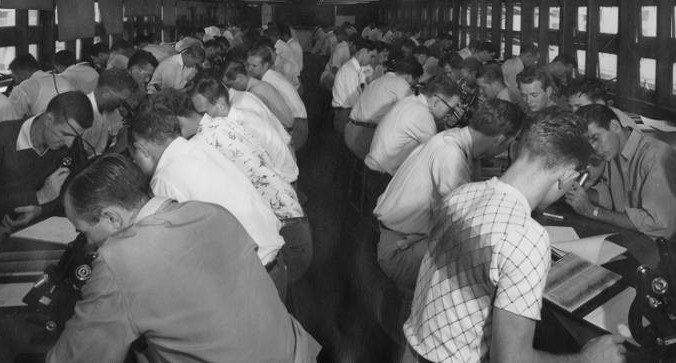 Students sit at long rows of tables and look into microscopes