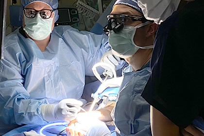 Drs. and nurses in scrubs performing carpel tunnel hand surgery.