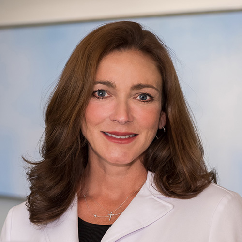 Dr. Stiles, a smiling woman with long brown hair, wearing a lab coat.