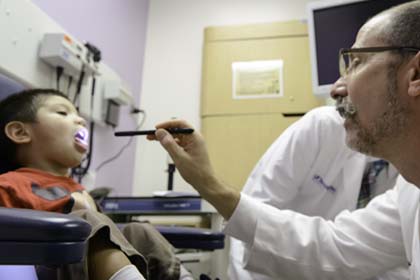 Doctor examining the mouth of a small child.