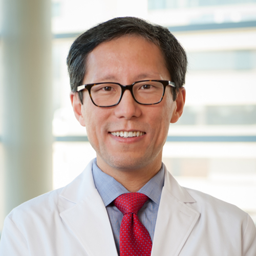 Dr. Cheng, a smiling man with dark hair and glasses, wearing a lab coat over a blue shirt and red tie.