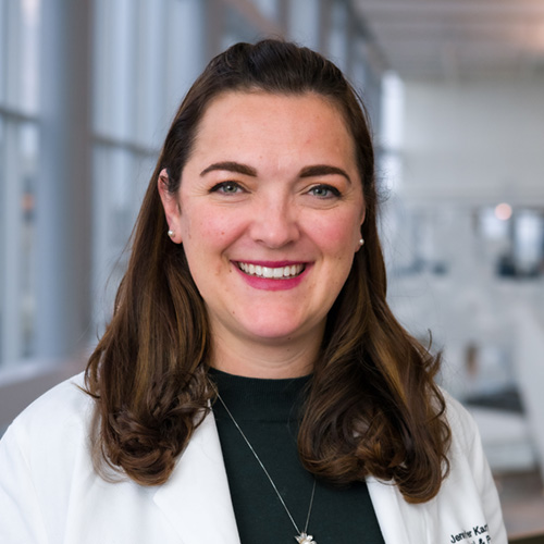 Dr. Kargel, a smiling woman with long, dark hair, wearing a lab coat over a dark shirt.