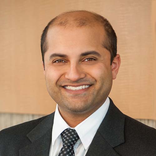 Dr. Nagarkar, a smiling man with dark, thinning hair, wearing a dark suit and polka-dot tie.