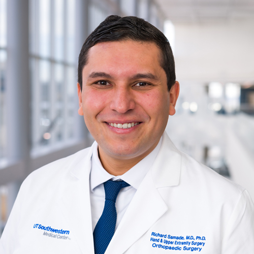 Smiling Man with dark wavy hair, wearing a lab coat.