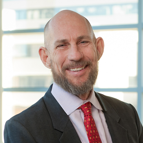 Dr. Thornton, a smiling man with a shaved head, beard and mustache, wearing a suit.