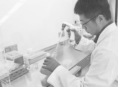 Man in white labcoat extracting fluid from jar