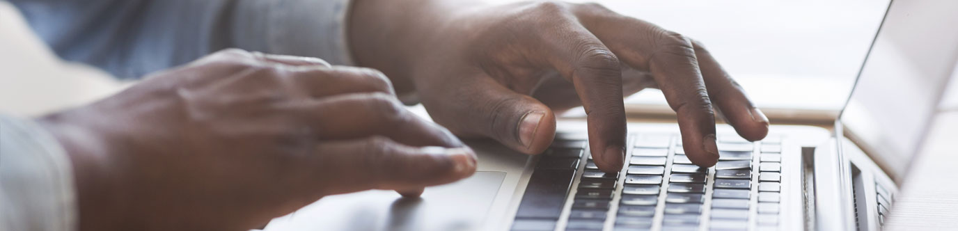 A Black man's hands on a laptop keyboard