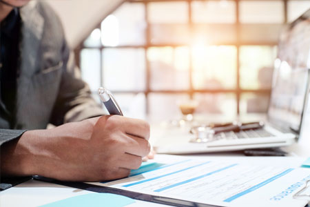 A man uses a pen to write on a paper form