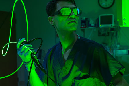 Green light highlights a man wearing glasses and the hose he is holding