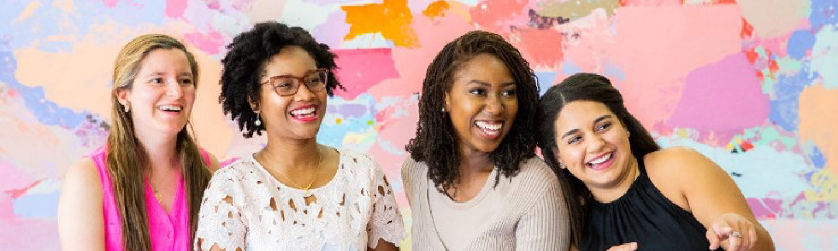 Four women in front of a multicolored background