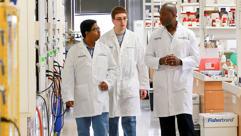 Students in lab coats walking in a lab