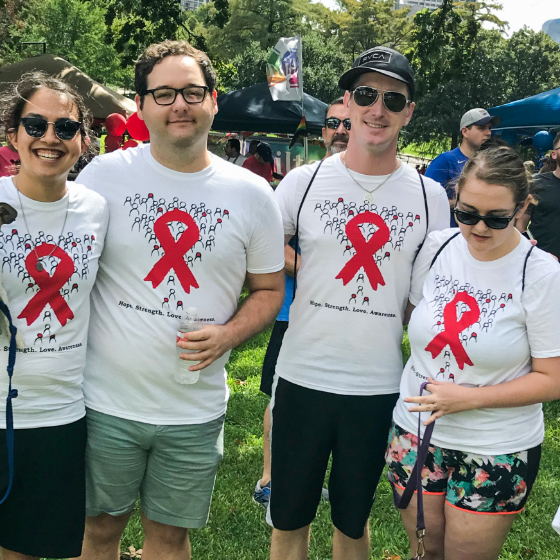 Two men and two women wearing white t-shirts with red ribbons