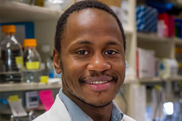 Man with short dark hair wearing white lab coat