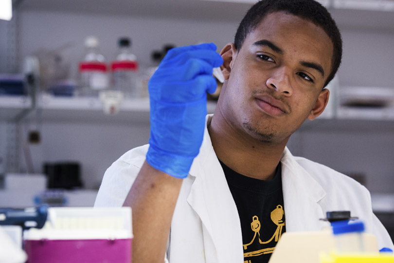 A male student holds a pipette in a lab