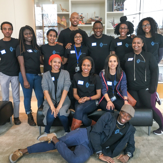 13 Black men and women pose with one lying on the floor, four sitting, and eight standing behind them