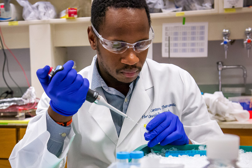A postdoctoral scholar in the research lab. Postdoctoral scholar fills a pipette in the research lab