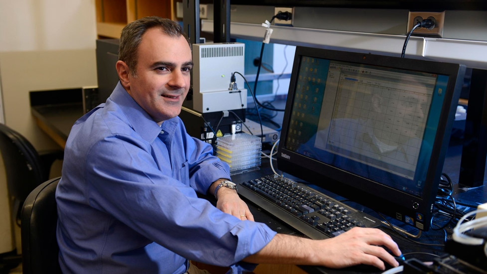 Dr. Ralph DeBerardinis sits at a computer in his lab