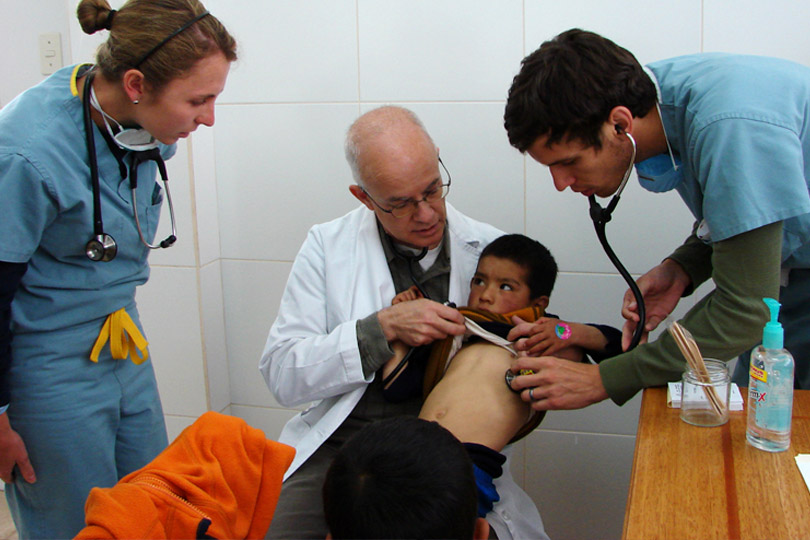 Two medical students check a young boy's heart beat in a medical clinic. Two medical students check a young boy's heart beat in a clinic