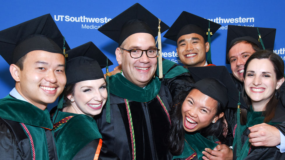 A faculty with a number of students in graduation garb