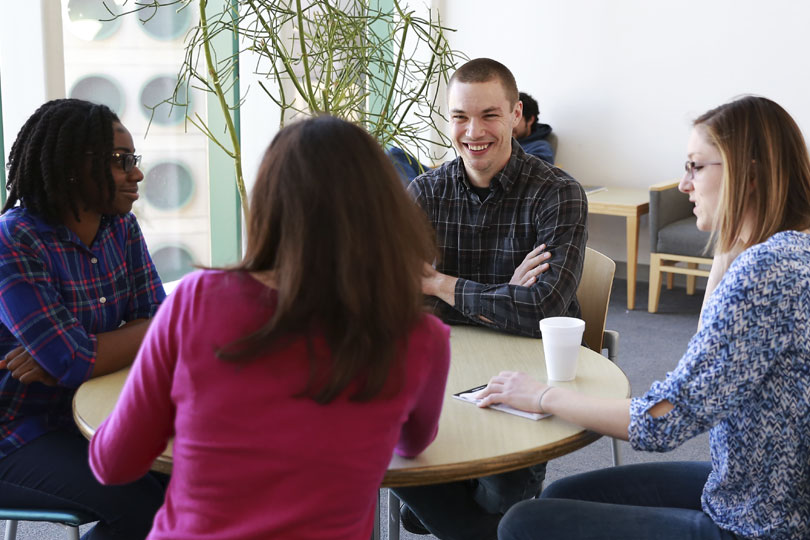 MSTP students enjoy a break. Three women and a man sit around a table