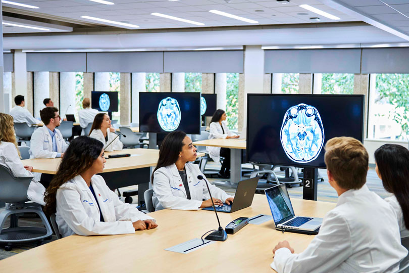 Medical students looking at a scanned image of a brain on video monitors in the Team-Based learning Center