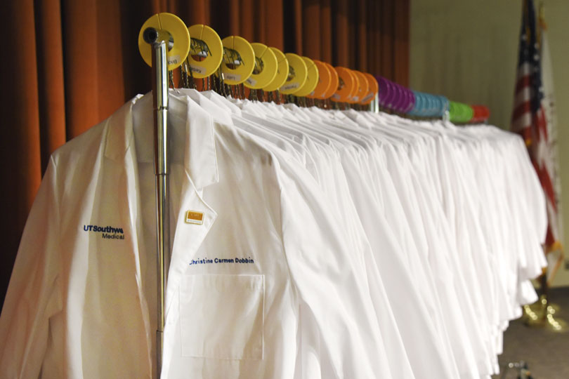 White coats hang on a rack at the White Coat Ceremony.