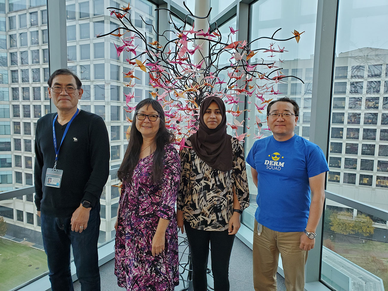 Four people standing in front of a window