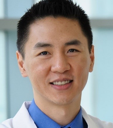 Man with short dark hair wearing a lab coat