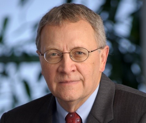 Man in dark grey suit wearing glasses