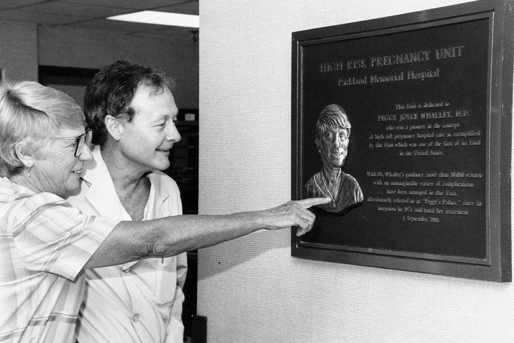 Dr. Peggy Whalley and a man look at a plaque at Parkland Memorial Hospital in her honor