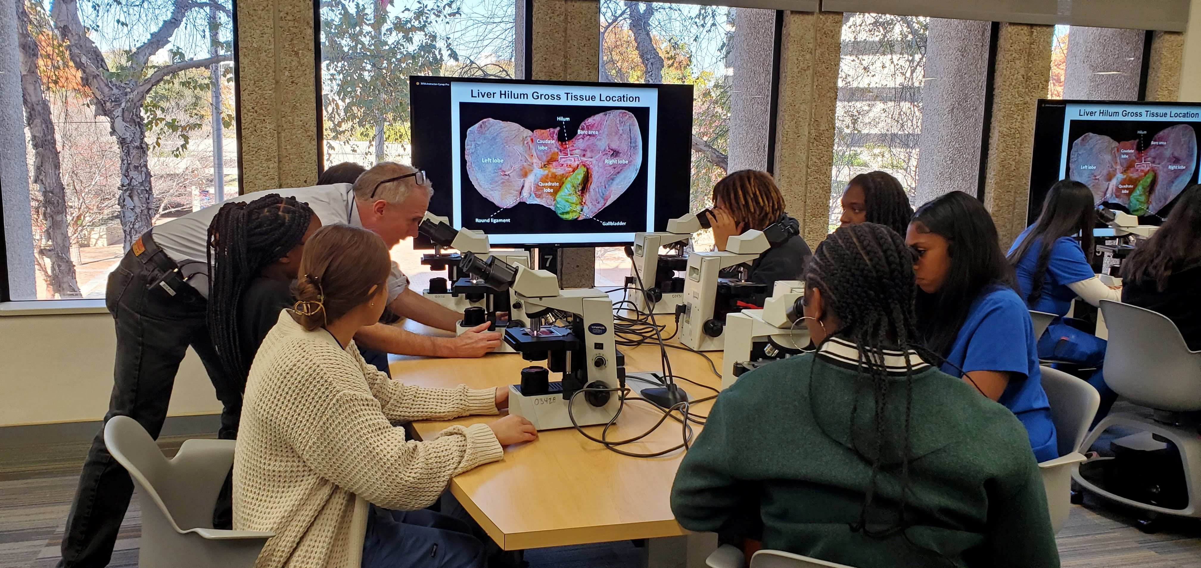 High school students learn about how to identify tissue and arteries by microscope from Dr. Peter Michaely