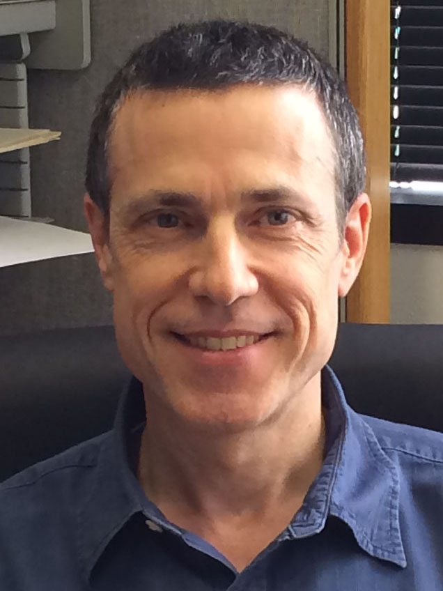 Smiling man with short dark hair, wearing a blue shirt.