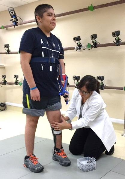 A women kneels to adjust a man's knee brace