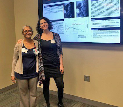 Two women stand in front of a poster