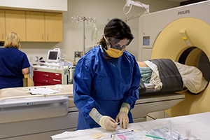 Two people in scrubs with patient in scanner