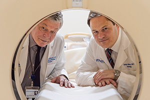 Robert Lenkinski and Suhny Abbara looking through the core of an MRI machine