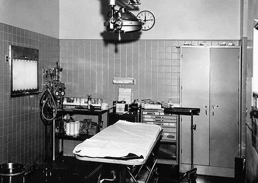 A room full of medical equipment with an empty bed in the center