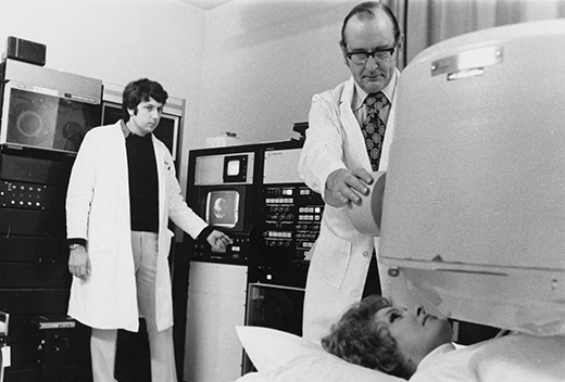 Doctors perform scan on a woman lying beneath large equipment 