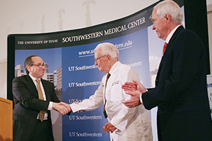 Mr. Clements, wearing an honorary doctor's coat, shakes hands with Daniel Podololsky