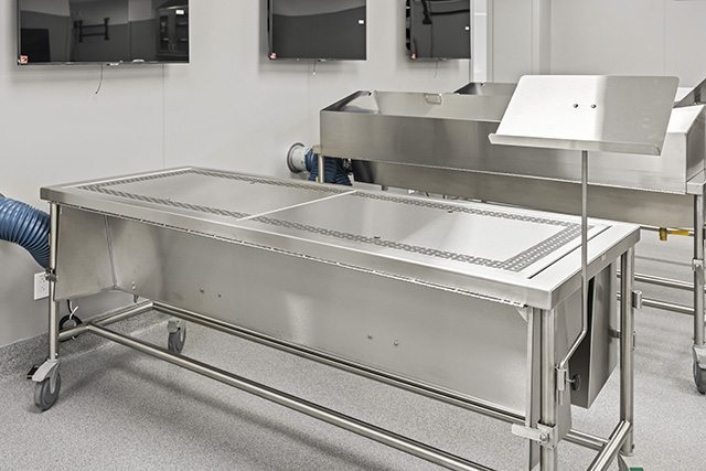 Stainless steel tables on wheels alongside computer monitors hung on the walls in a section of the anatomy lab.