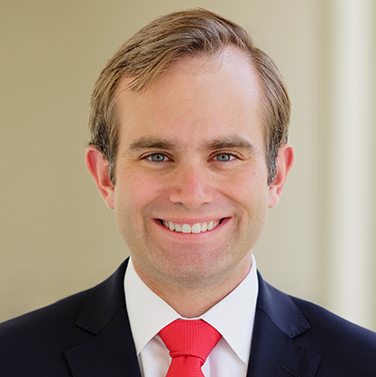 Andrew Shubin, a smiling man with light brown hair, wearing a suit and red tie.