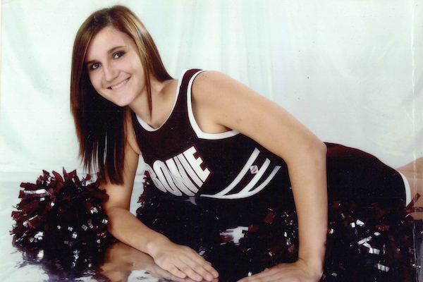 Chelsea wearing her high school cheerleader uniform and with pompoms.
