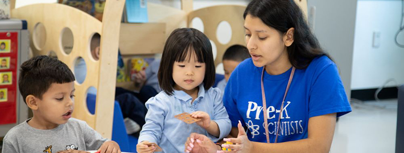 Female teacher with two students at table in classroom