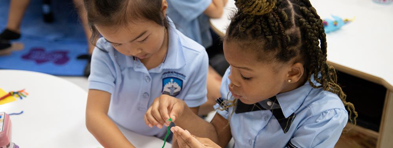 Two young female students working on a project together in a classroom