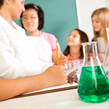 Middle school female students speaking with teacher in class