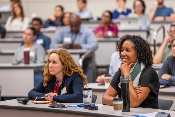 two female students in audience engage with lecture