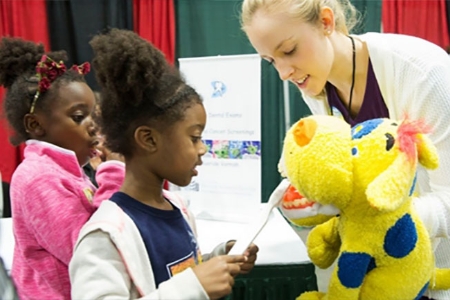 A woman interacting with two little girls at event