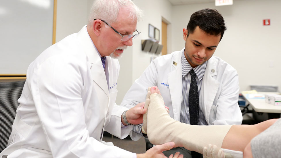 Faculty member helping student set an injured leg